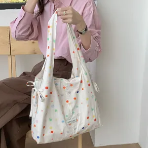 Detail van canvas polkadot vesttas met schattige strikbandjes en grote opbergcapaciteit.