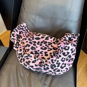 Gedetailleerd overzicht of roze zwarte luipaard corduroy schoudertas met plooien.
