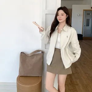 Close-up detail of casual brown suede tote bag and autumn outfit in indoor scene, minimalist.