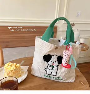 Detailed view of the cute corduroy tote bag with embroidered puppy and green handles.