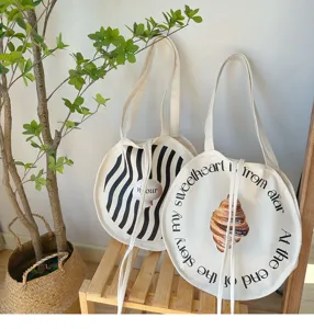Detailansicht der runden Segeltuchtasche mit künstlerischem Buchstabendruck und Mustern.