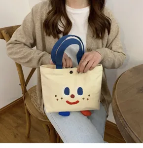 Vue de détail du joli sac fourre-tout en toile avec visage de dessin animé brodé et petits pieds.