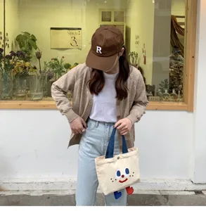 Sac à lunch bento en toile mignon avec visage de dessin animé et jambes pendantes.