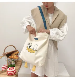Cute Daisy Duck canvas tote bag with large capacity, contrast shoulder strap and cute yellow duck feet.