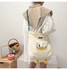 Beige canvas shoulder bag with cute cartoon duck face print and 3D feet, large capacity.