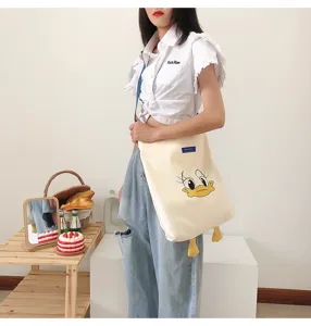 Details of a casual canvas shoulder bag featuring a cute cartoon duck print and large capacity.