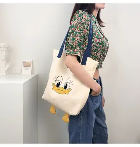 Detail view of the large capacity canvas tote bag with cute cartoon duck face and dangling feet.