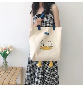Detail view of a cute cartoon duck canvas tote bag with contrast shoulder straps and duck feet.