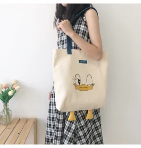 Detail view of the canvas tote bag with cute cartoon duck face and hanging feet design.