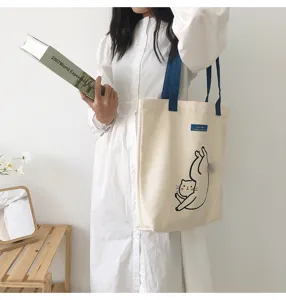 Canvas tote bag with cute cat graphic and blue contrast straps, casual large capacity shoulder bag.
