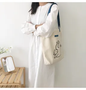 Casual canvas tote bag featuring cute cat print and blue contrast straps for daily wear.