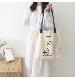 Cute canvas tote bag featuring playful cat print detail and convenient blue shoulder straps.