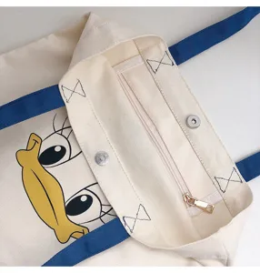 Canvas tote bag detail view, cartoon duck print, blue straps, metal snap button closure.