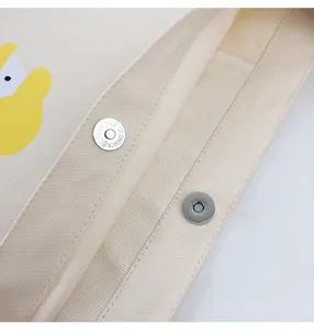 Canvas bag detail showing durable beige fabric texture and secure magnetic snap button.