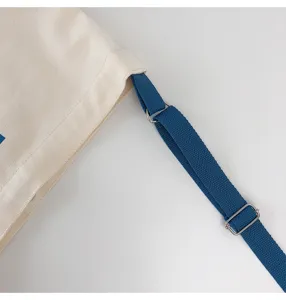 Canvas shoulder bag detail view showing blue adjustable strap and metal hardware.