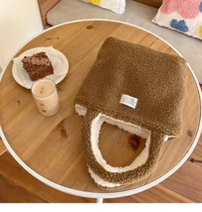 Braune flauschige Tasche Detailansicht mit weicher Teddyfleece Textur und Stofflabel auf Holztisch.