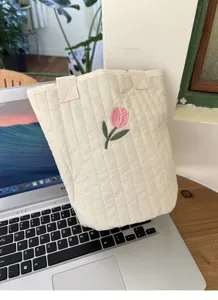 Detail close-up shot of a quilted canvas handbag featuring cute pink tulip embroidery.
