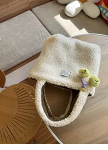 Nahaufnahme der süßen Plüsch-Tragetasche mit weichem Teddy-Stoff und verspieltem Frucht-Anhänger.