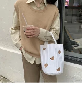 Detailed view of white quilted bucket bag with cute bear embroidery, casual daily style.