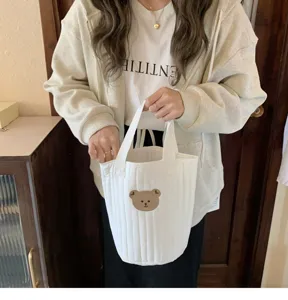 Detailed view of white quilted canvas bucket bag with cute bear embroidery, perfect for daily use.