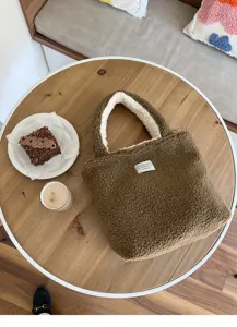 Braune Plüsch-Tragetasche Detail mit flauschiger Textur, weißem Futter und süßem Etikett.