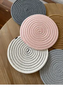 Close-up of woven cotton coasters and heat insulation pads in various colors on a wooden table.