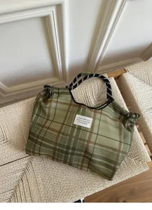 Detailed view of green plaid canvas cradle tote bag with rope handles and text tag.