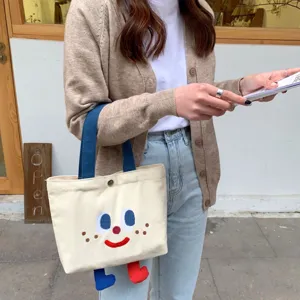Sac cabas en toile mignon avec visage de dessin animé, petit sac à main pour le déjeuner.
