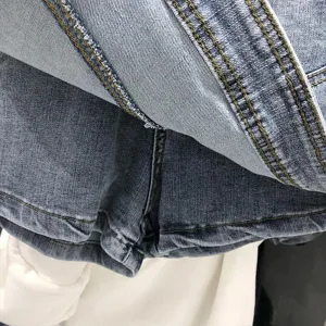 Nahaufnahme der Jeans-Skort-Details mit gelben Kontrastnähten und blauer Waschung.