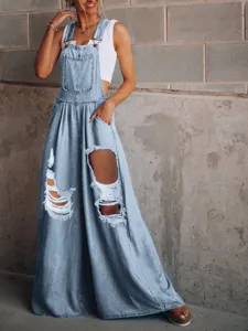 Distressed light wash denim overalls detail shot showing ripped knees and loose wide-leg fit style.