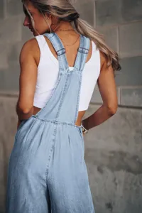 Women casual loose denim overalls detailed view, stylish light blue back view apparel shot.