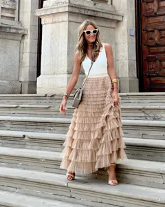 Detailed view of the layered mesh tulle tiered cake skirt in soft beige, outdoor scene.