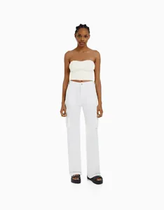 Detailansicht des weißen trägerlosen Bandeau-Tops und der passenden High-Waist-Cargohose.