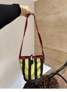 Retro gestreifte Segeltuch Eimer Tasche Detail, grün braune vertikale Streifen mit rotem Gurt.