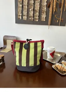 Detailansicht der retro gestreiften Segeltuch-Eimer-Tasche mit grünen vertikalen Mustern.