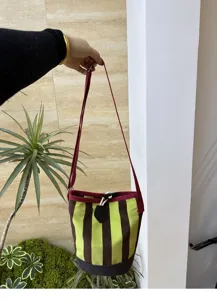 Canvas-Beutel mit lebendigen vertikalen Streifen, verstellbarem rotem Riemen und stilvollem Kordelzugverschluss.