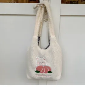 Detailed view of fluffy white plush shoulder bag featuring cute bear and peach embroidery.