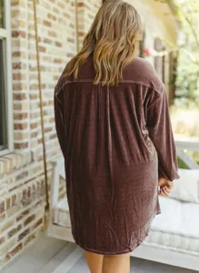 Detailed view of a stylish brown velvet oversized shirt dress worn outdoors by a model.