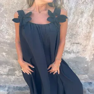 Summer black sleeveless women dress with elegant flower shoulder straps detail close up look.