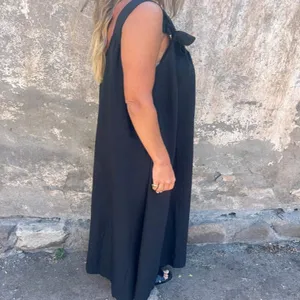 Detail view of the elegant black sleeveless maxi dress featuring stylish shoulder strap knot.