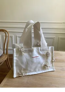 Detail view of the white canvas mini tote bag featuring exquisite 3D floral appliques and handles.