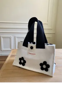 Mini canvas tote bag with black handles and cute floral appliques for daily portable use.