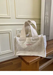 Detailed view of mini floral textured canvas tote bag with dual handles, clean neutral aesthetic.