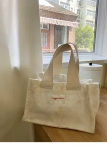 Detailed shot of mini canvas tote bag with floral jacquard pattern and sturdy handles.