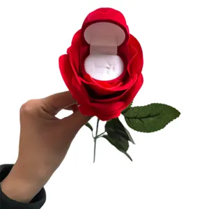 Detailed shot of red flocked rose ring box with stem and leaf, open display interior velvet slot.