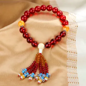 Close-up detail of red crystal prayer beads car hanging ornament with tassel and amber beads.