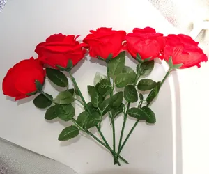 Close up view of red artificial roses with green leaves and stems, detail display.