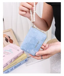 Vue détaillée du porte-cartes en suédine bleu clair avec élégante lanière de perles.
