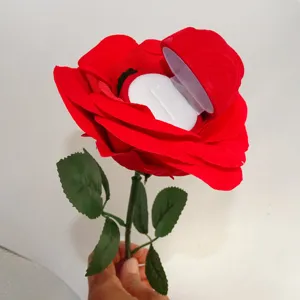 Flocked red rose ring box with long green stem for romantic proposal and jewelry gift presentation.