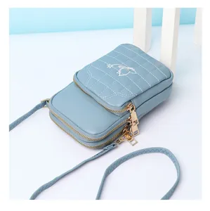 Light blue quilted mini crossbody phone bag detail, double zipper design with cute embroidery.